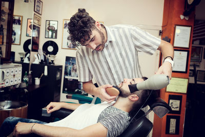 Barber grooming customer in shop