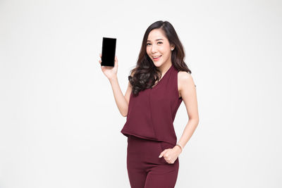 Portrait of a smiling young woman standing against white background