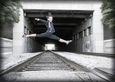 Full length of teenage girl jumping over railroad track