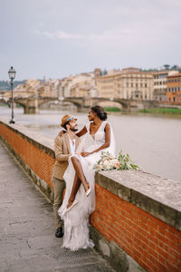 Couple holding umbrella on bridge against sky