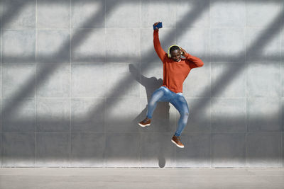 Full length of man jumping against wall
