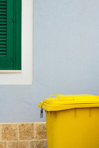 Yellow garbage can outside house