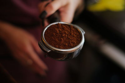 Cropped hand of women holding coffee powder in porta filter