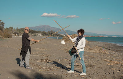 Full length of man holding umbrella on beach