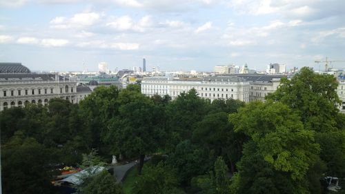 Trees and buildings in city against sky