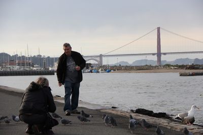 Full length of man standing on suspension bridge over river