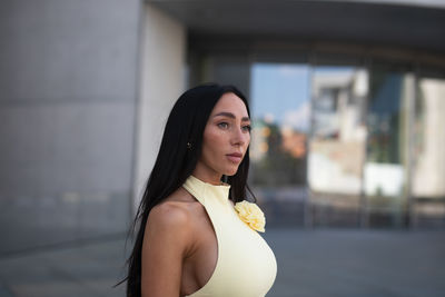 Portrait of young woman looking away against wall