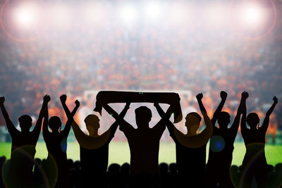 Close-up of silhouette people against illuminated sky at night