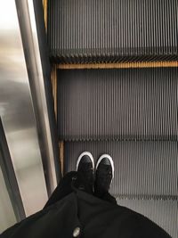 Low section of person standing on escalator