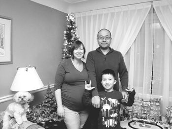 Portrait of parents standing with cheerful son at home during christmas