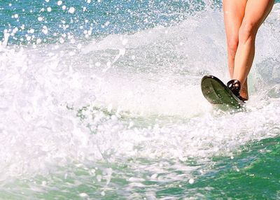 Low section of a woman surfing in the sea