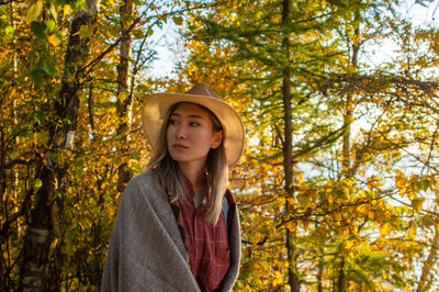 Portrait of beautiful young woman in forest during autumn