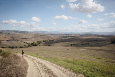 Scenic view of road amidst field against sky