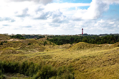 Lighthouse on field against sky