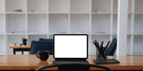 Cropped shot of workplace with tablet blank screen and office supplies in simple workspace