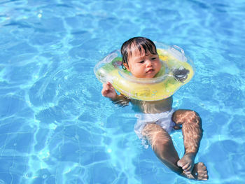 Baby learns to swim with extra swimming ring for babies