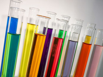 Close-up of multi colored chemicals in test tubes against wall