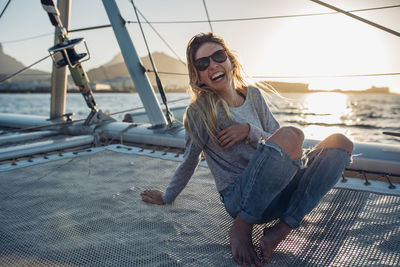 Portrait of young woman in boat on sea against sky