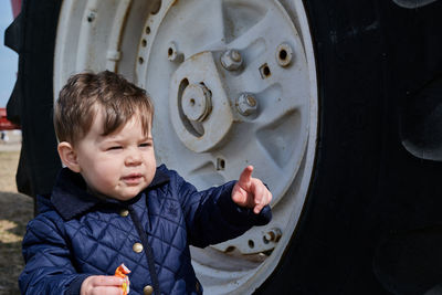 Little boy next to a huge tractor wheel at the county fair