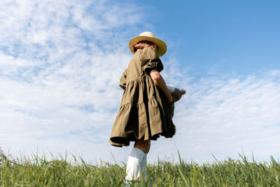 Girl in a linen dress and a straw hat walks . wicker basket in hands. wellness and freedom concept.