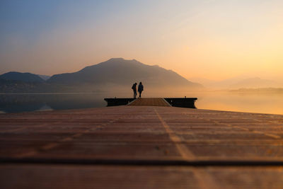 Silhouette man standing on shore against sky during sunset