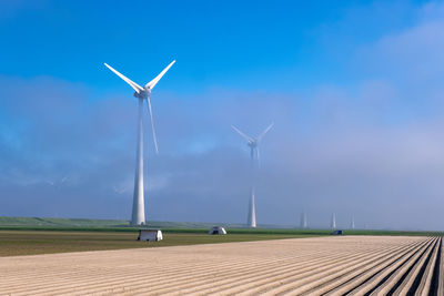 Wind turbines on field against sky