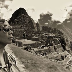 Woman standing on mountain against cloudy sky