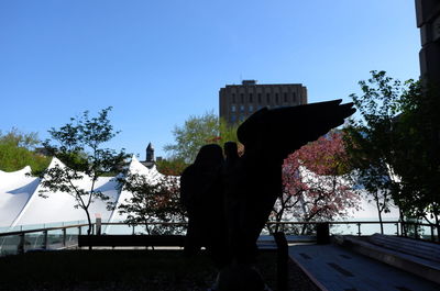 People standing by tree against clear blue sky