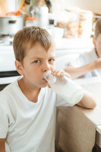 A boy is drinking milk from a bottle in the kitchen at home. morning breakfast with milk. 