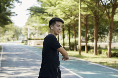 Side view of smiling young man standing on road