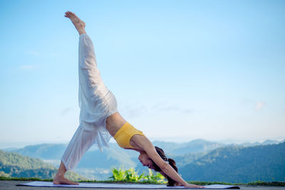 Midsection of woman with arms raised against sky