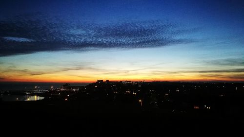 Silhouette cityscape against dramatic sky during sunset