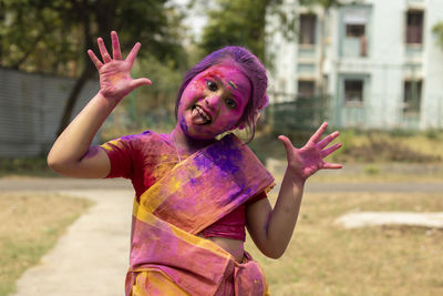 A pretty indian bengali girl child in saree and colorful face during holi