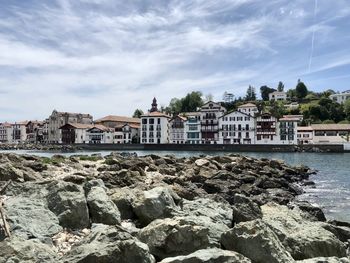 Buildings by sea against sky