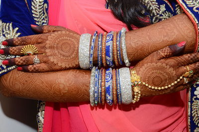 Midsection of bride with bangles and henna tattoo