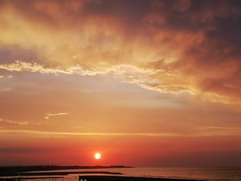 Scenic view of sea against dramatic sky during sunset