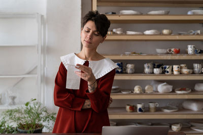Upset female pottery studio owner looking at receipt with worried facial expression