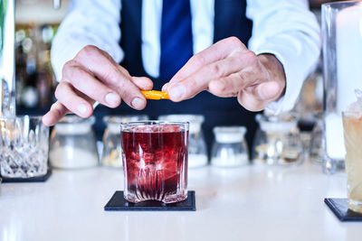 Midsection of man drinking glass on table at restaurant