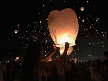 People in illuminated lantern against sky at night