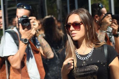 Man photographing with camera while woman wearing sunglasses