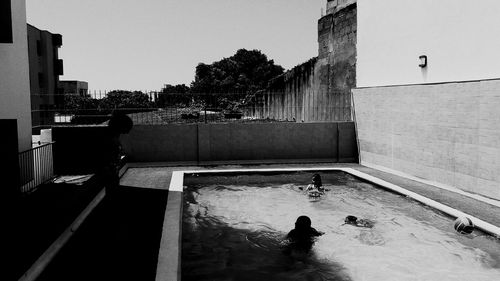 Children swimming in pool by building