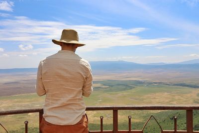 Rear view of man looking at crater against sky