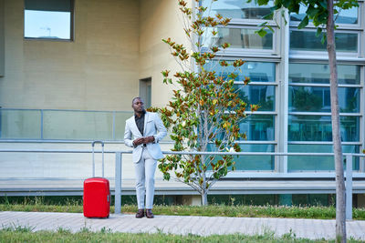 African-american in a white suit and a red suitcase. person