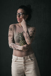 Portrait of young woman standing against black background