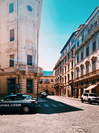 Cars on street by buildings against sky in city