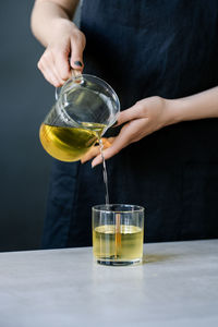 The girl pours wax into glass glasses with wicks.