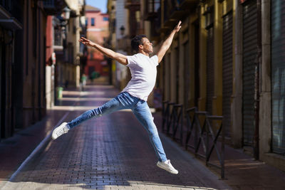 Full length of man jumping over street against building