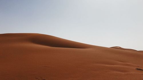 Sand dunes in desert against clear sky