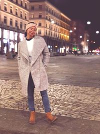 Portrait of young woman standing on street at night