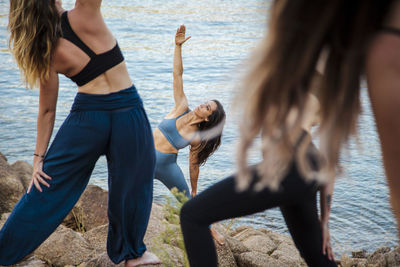 Young female yoga instructor teaching stretching exercise to women